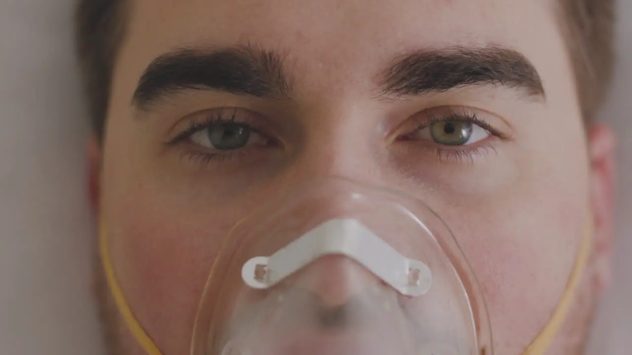 Close Up Of A Sick Man Breathing Through Oxygen Mask And Looking At Camera 1