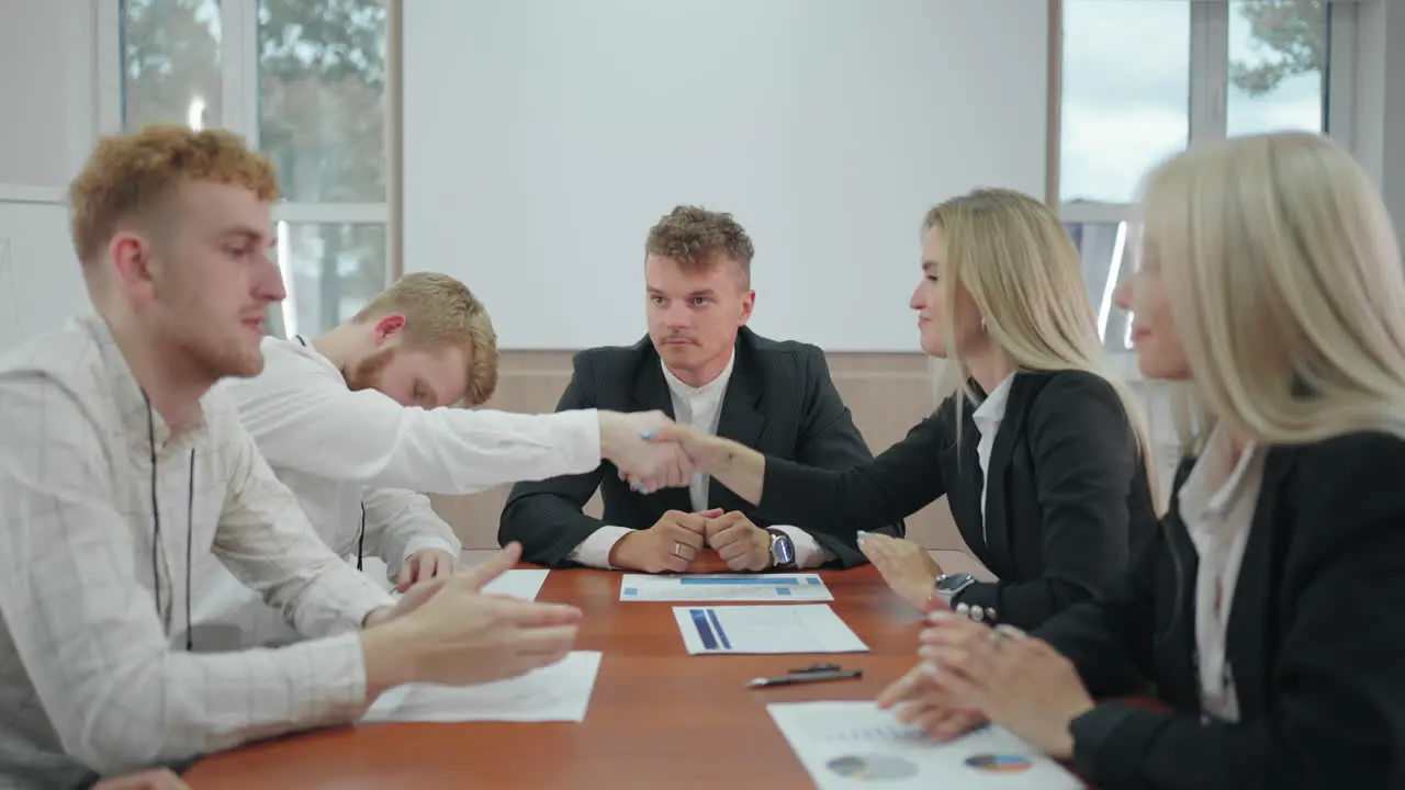 business negotiations in conference hall people are shaking hands sitting at long table