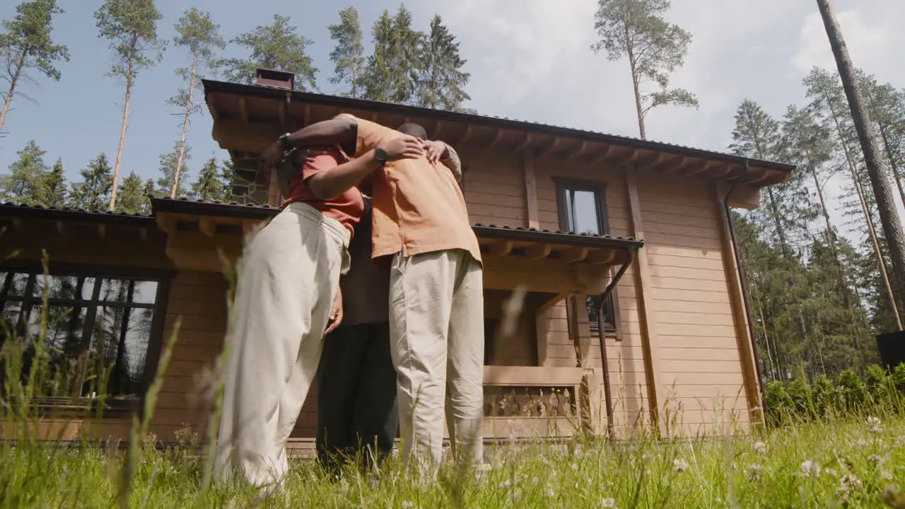 View From Below Of A Happy Family Talking And Hugging Outside Home In A Sunny Morning