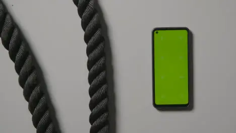 Overhead Studio Fitness Shot Of Hands Picking Up Gym Battle Ropes With Green Screen Mobile Phone On Grey Background 1