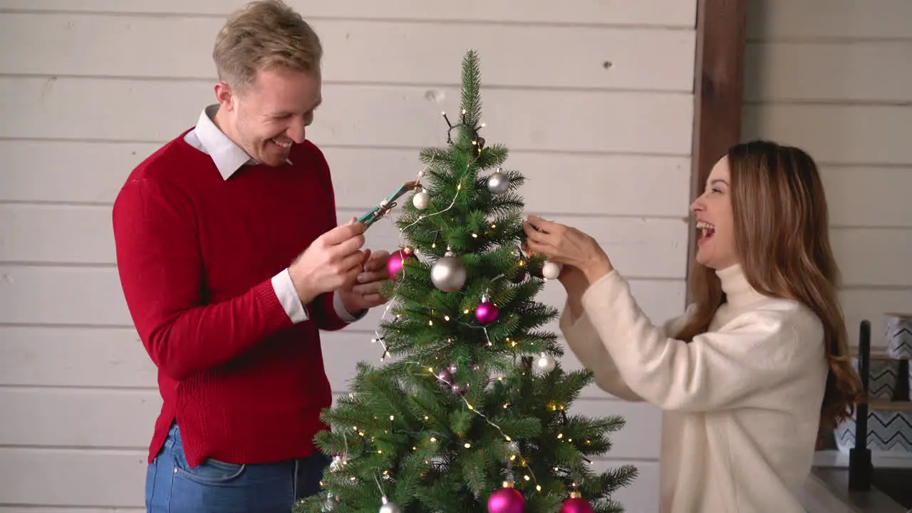 Glückliches Paar Hängt Weihnachtsdekoration Am Weihnachtsbaum Zu Hause 1