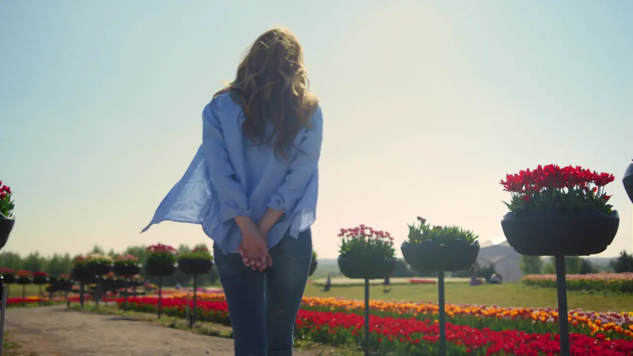 Vista Posterior De Una Chica Relajada Con Cámara Caminando En El Parque De Flores De Verano Bajo El Sol