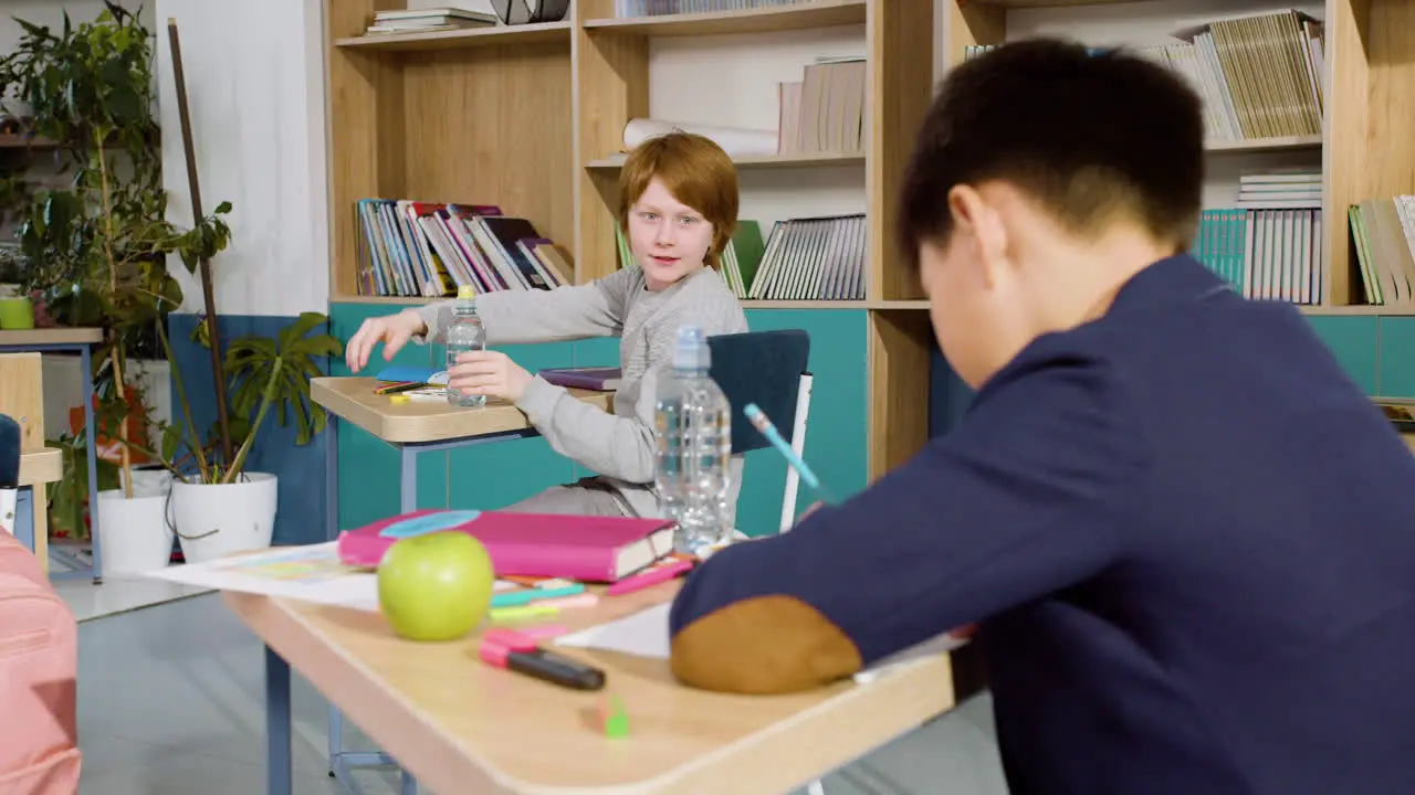 Der Verspielte Ginger Boy Redet Und Hat Spaß Mit Seinem Amerikanischen Klassenkameraden Während Er Am Schreibtisch Im Klassenzimmer Sitzt