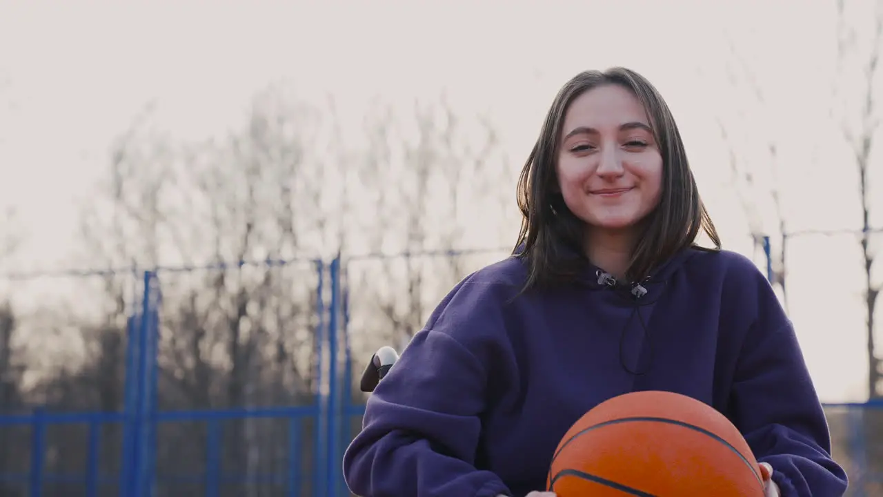 Glückliche Behinderte Frau Im Rollstuhl Die In Die Kamera Blickt Während Sie Einen Basketball Auf Dem Basketballplatz 1 Hält