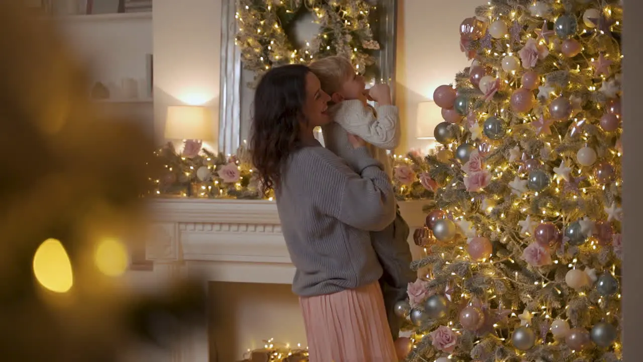 Der Kleine Junge Schmückt Den Weihnachtsbaum Mit Kugeln Und Ornamenten Die Mutter Hebt Ihn Hoch