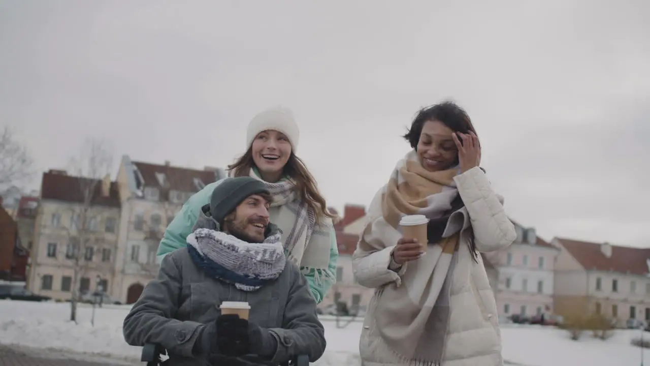 Behinderter Mann Im Rollstuhl Und Zwei Frauen Die Im Winter 1 In Der Stadt Spazieren Und Miteinander Reden