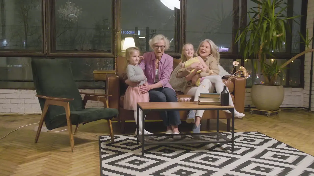 Dos Niñas Corriendo Y Abrazando A Sus Abuelas Felices Que Se Sientan En El Sofá En La Sala De Estar En Casa