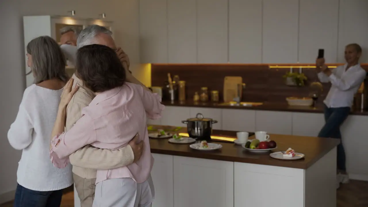 Dos Felices Parejas Mayores Bailando En La Cocina Mientras Que En Un Fondo Borroso Una Anciana Bonita Los Filmaba En El Teléfono Móvil 1