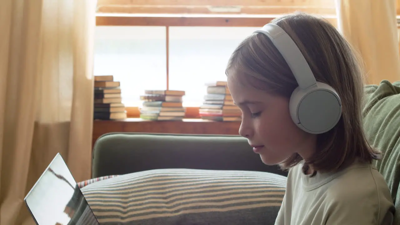 Primer Plano De Una Niña Rubia Feliz Con Auriculares Mirando La Pantalla Del Portátil