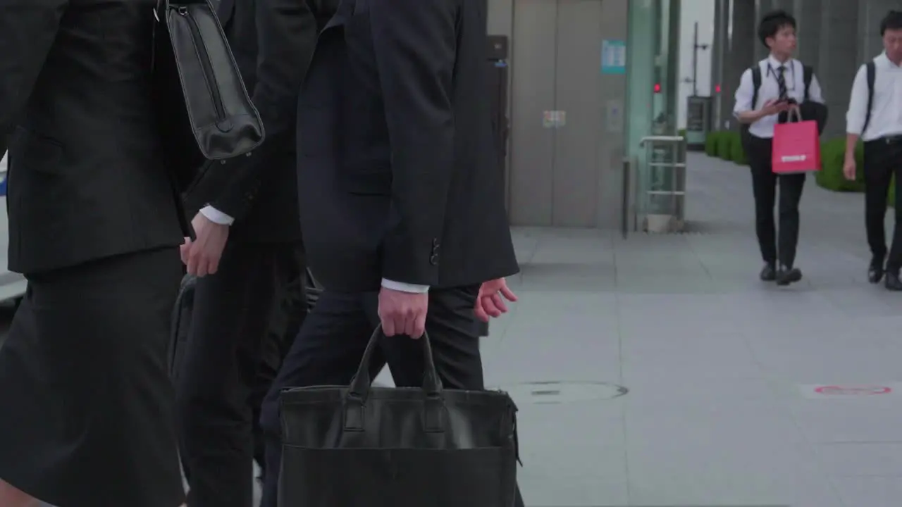 japanese business people cross a street in tokyo japan in business attire