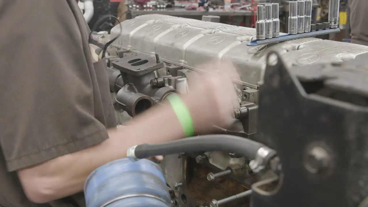 Diesel mechanic ratchets a bolt on the side of a Diesel engine slider shot no face