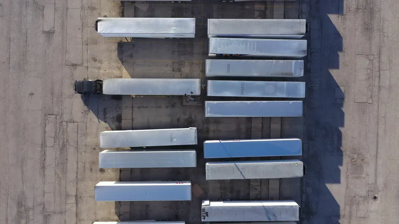 large fleet of containers and tractor trailers in warehouse lift up vertical aerial