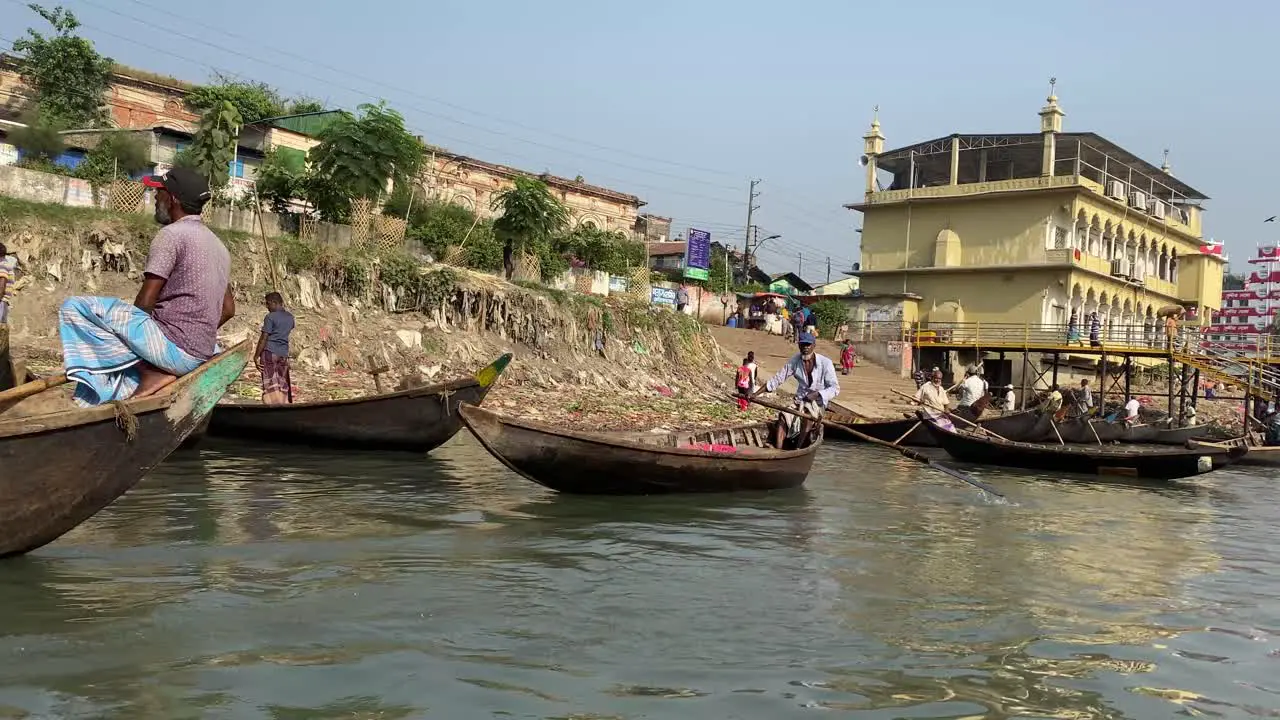 Locals with their unique boat taxis rowing past on the Buriganga river bank Dhaka