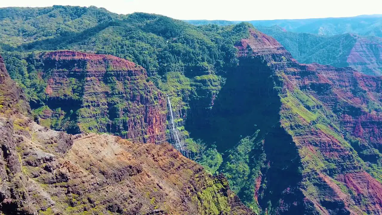 HD Hawaii Kauai slow motion wide shot of Waimea Canyon with a helicopter in the distance near a waterfall that flies away