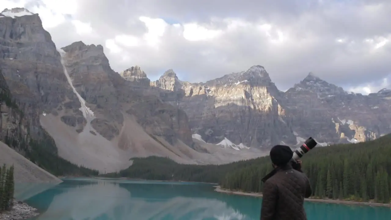 A travel Photographer standing near a blue lake in Banff Canada