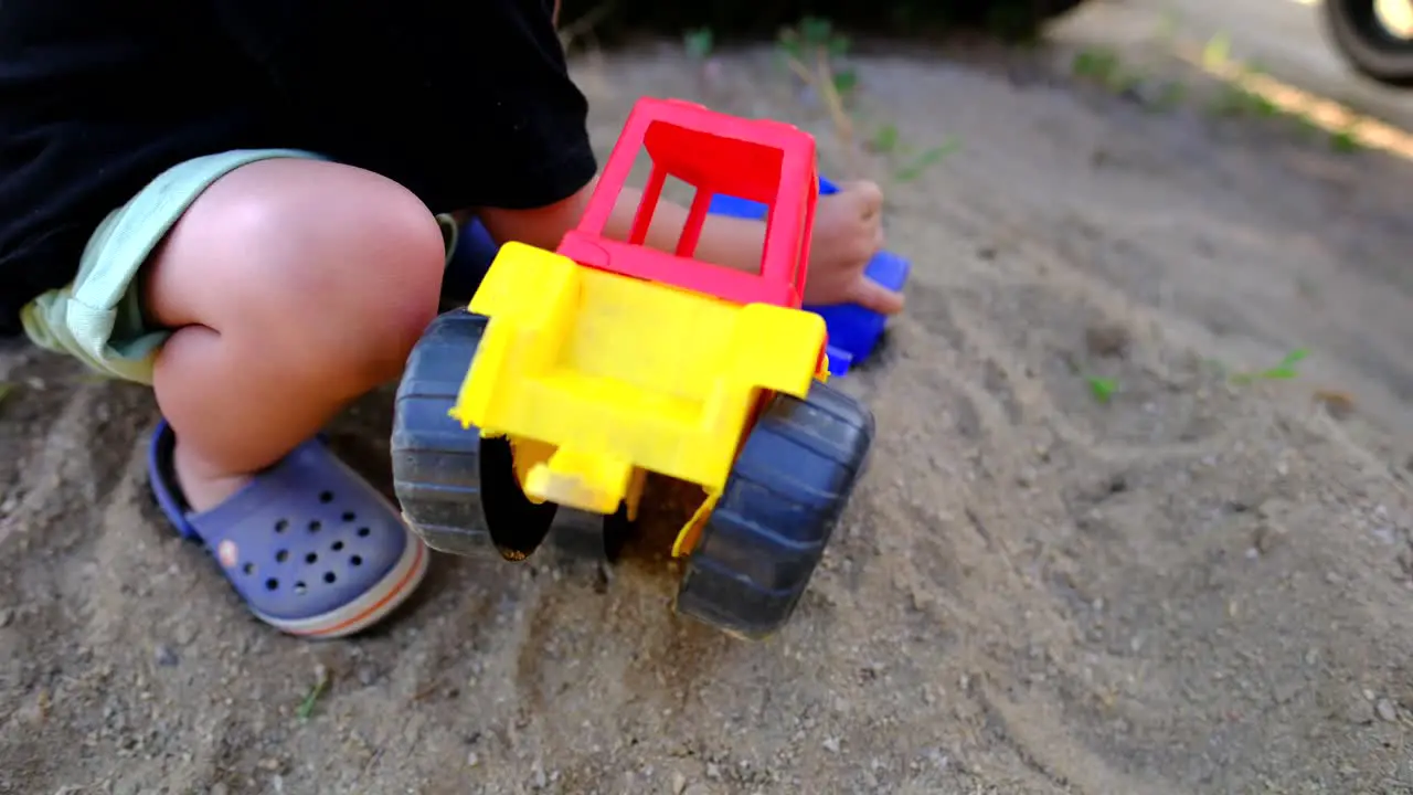 toddler playing with soil with his toy tractor