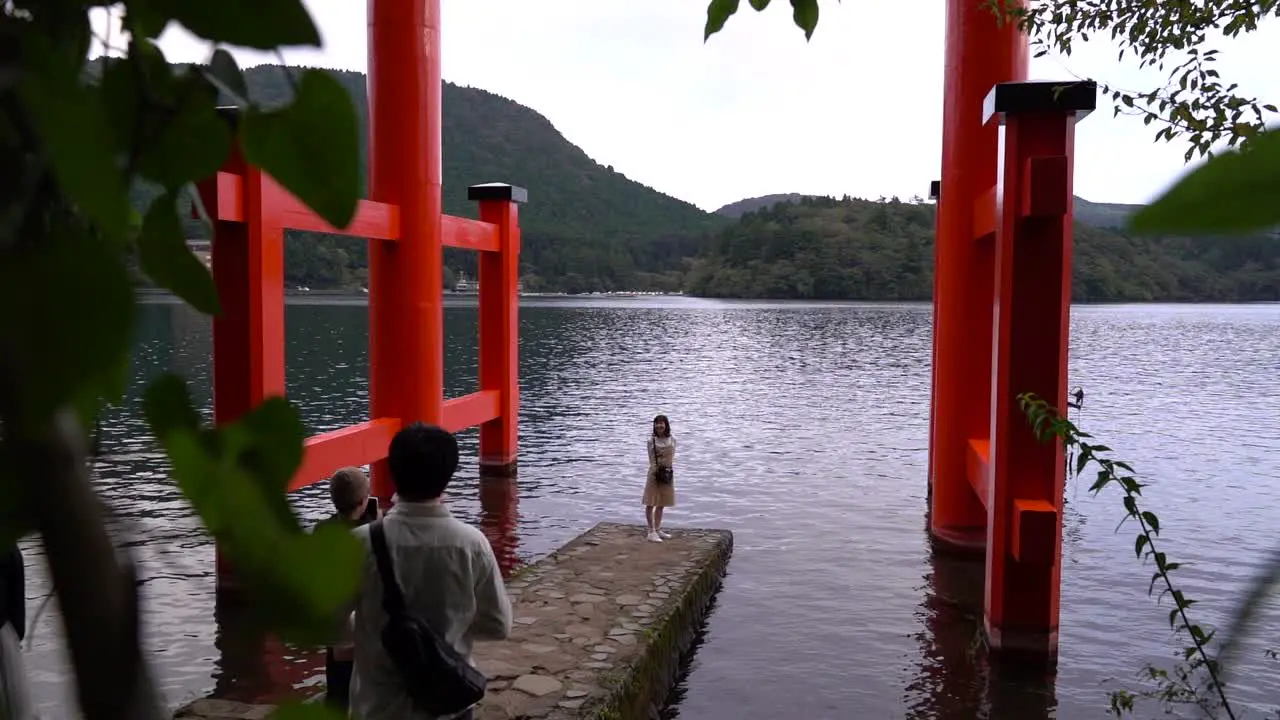 Slow motion push out between trees at Hakone Shrine with happy girl posing