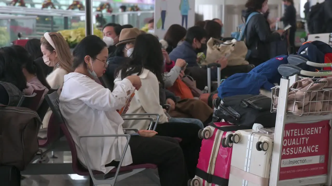 Passengers and Chinese tourists sit at the departure hall in Hong Kong Chek Lap Kok International Airport