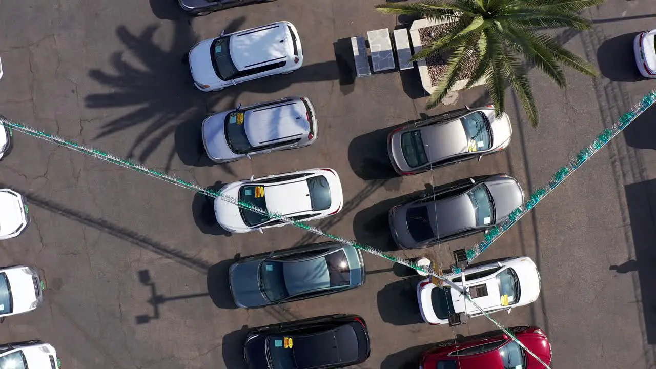 Rising bird's eye spiral aerial shot of rows of cars at a used car dealership