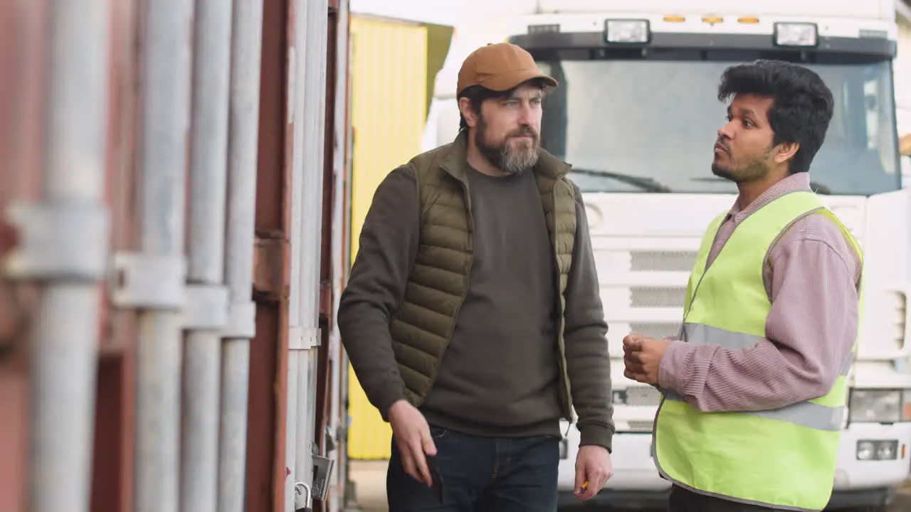 Boss And Worker Organizing A Truck Fleet In A Logistics Park While They Watching Something On A Smartphone