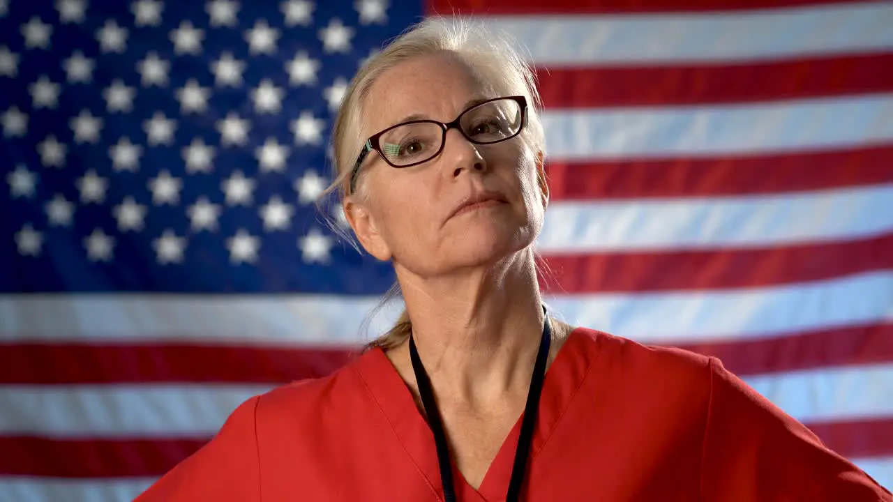 Portrait of a nurse showing a seriousness and disapproval set against an out of focus US flag