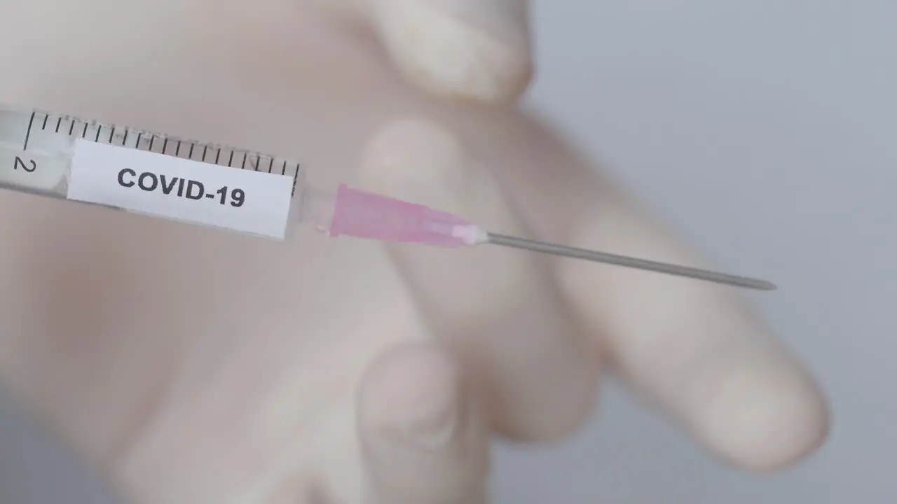 Hand With Glove Flick Off The Syringe With Covid 19 Vaccine Close Up Shot