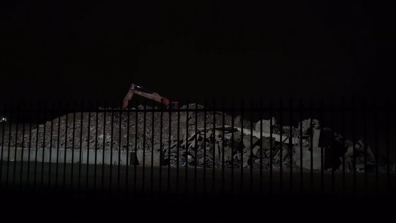 Concrete rubble and excavator at night wide