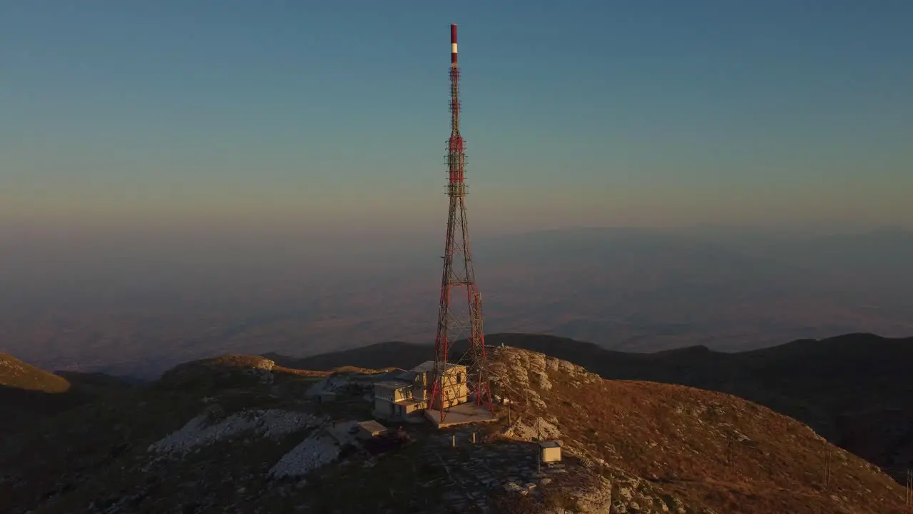 Aerial of tall telecommunications tower on a mountain peak at sunrise