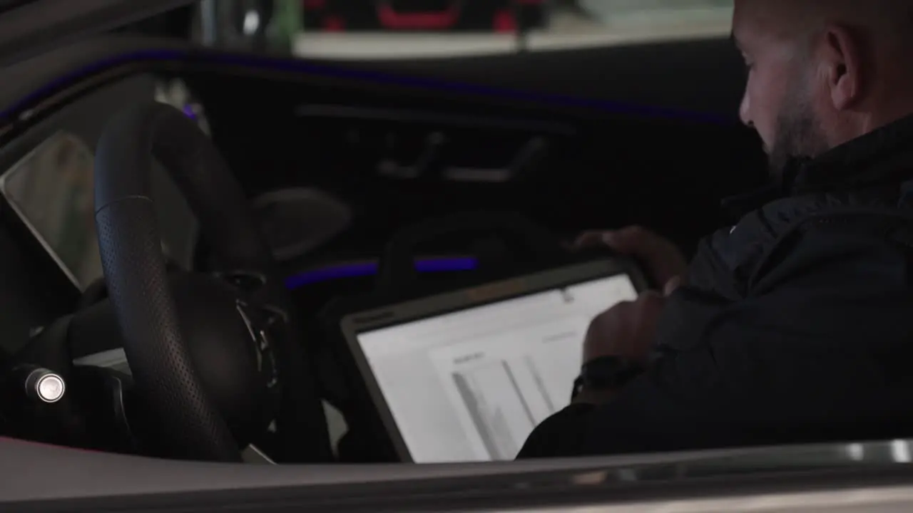 Mechanic sitting in a Mercedes car using the touch screen in the car