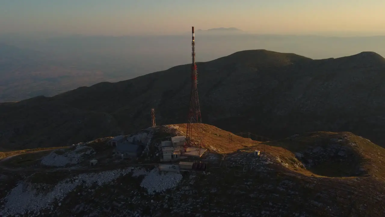 Slow aerial of telecommunications tower on a mountain peak at sunrise