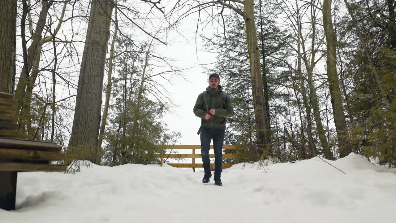 Young Male Hiker with backpack walks away from view point in winter forest