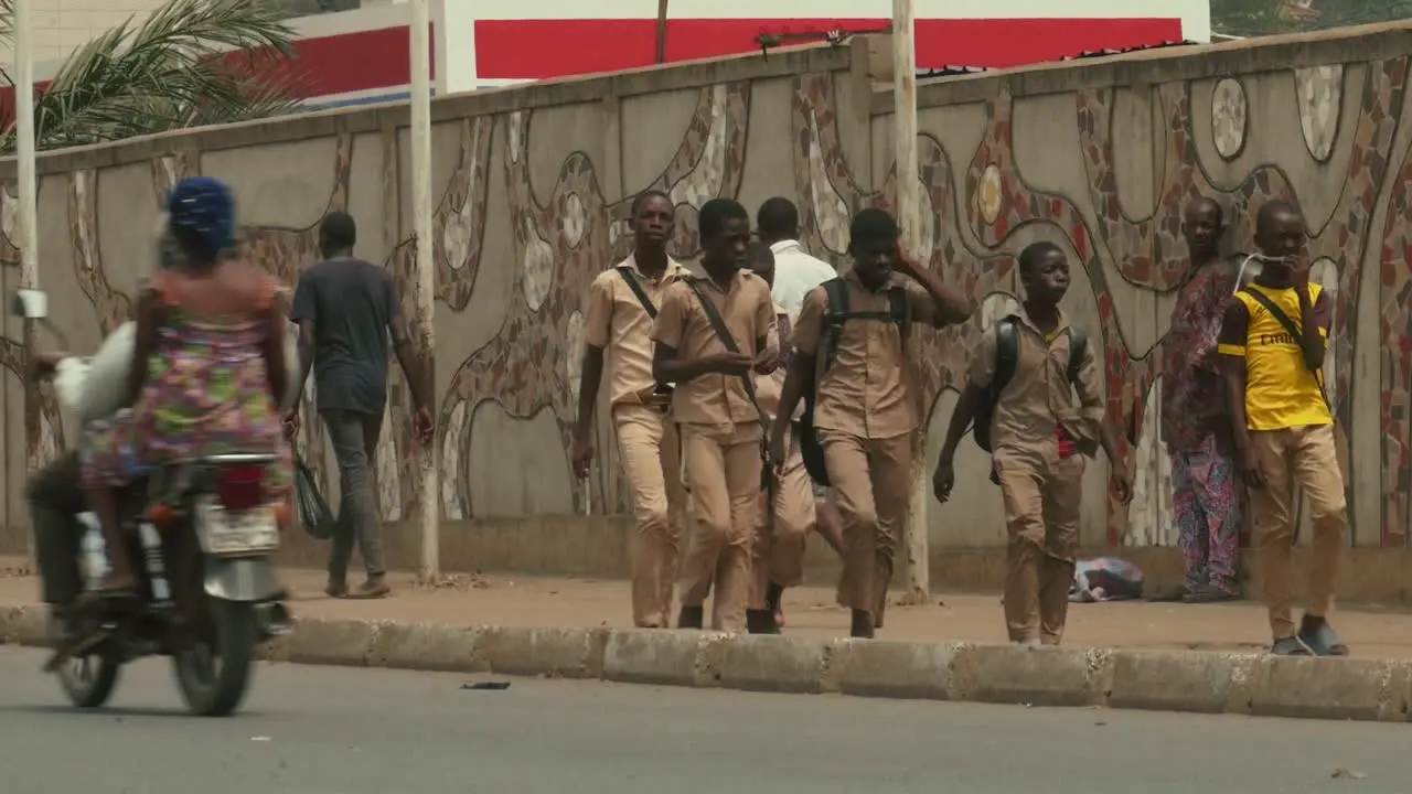 African students walking on roadside with cars and motorcycles passing in foreground Togo Africa