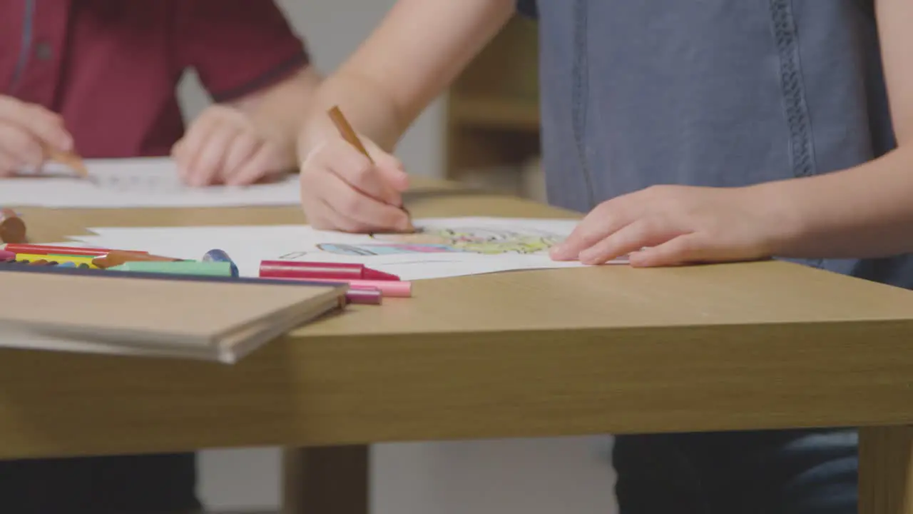 Close Up Of Children At Home Colouring In Pictures Of Food At Table