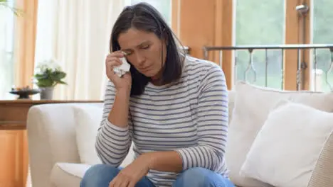 Tracking Shot Orbiting Around Visibly Upset Woman Dabbing Eye with Tissue