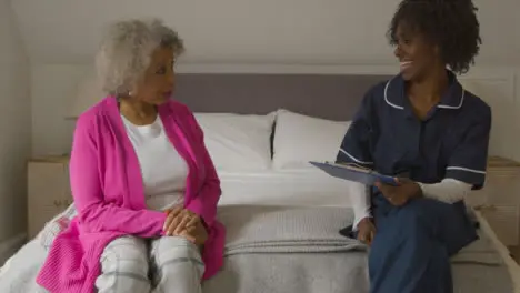 Middle Aged Nurse Conducts Home Visit with Senior Woman