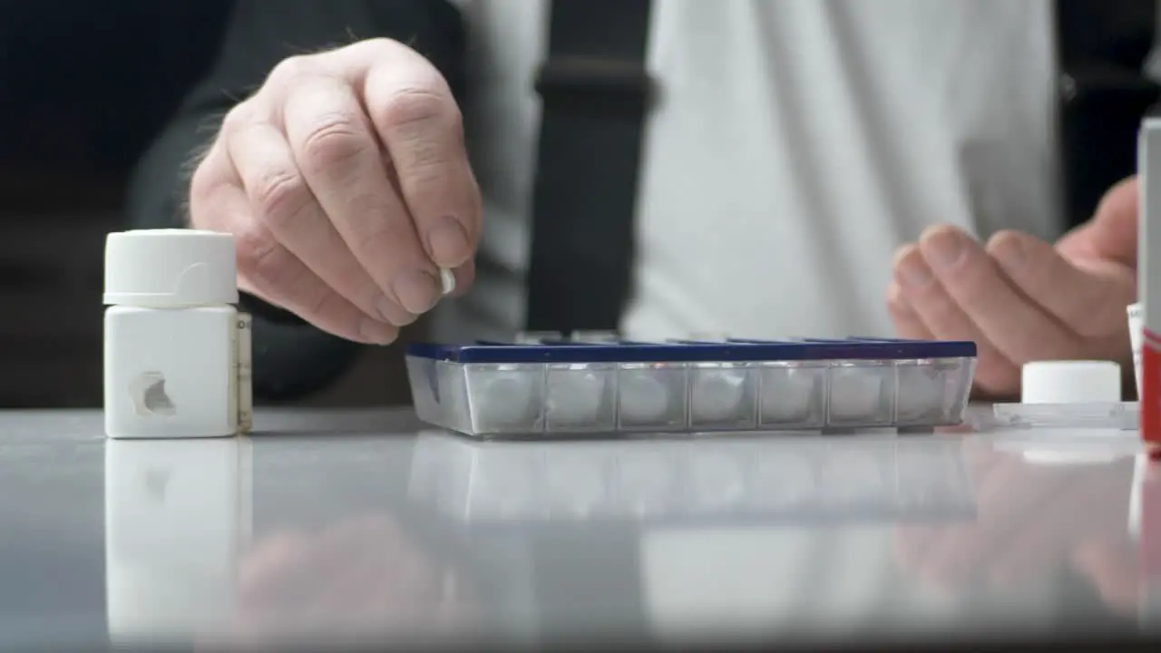 Old man dividing his weekly pills by the Medicine pill case Static close up shot