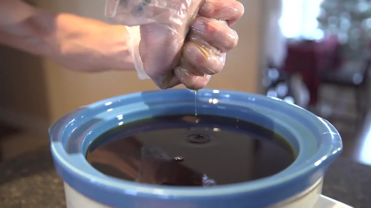 Person Squeezing Excess Liquid From Teabag Unto Pot Medical Marijuana close up shot