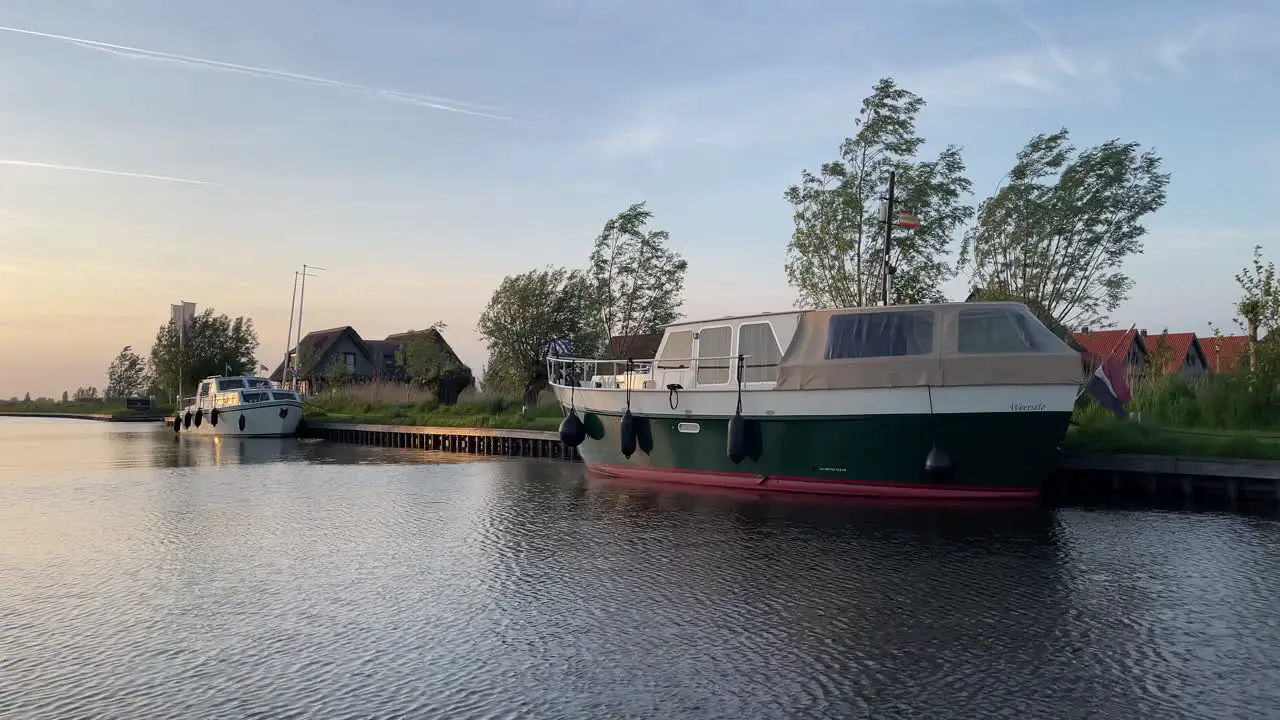 Cruising Across The River Passing By Boats On The Riverside Near Luxury Holiday Park In Ossenzijl Netherlands At Sunset