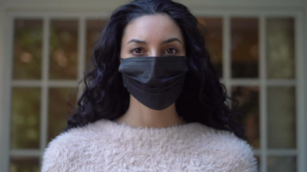 Young attractive Latina woman puts on a face mask to protect herself and others from infection