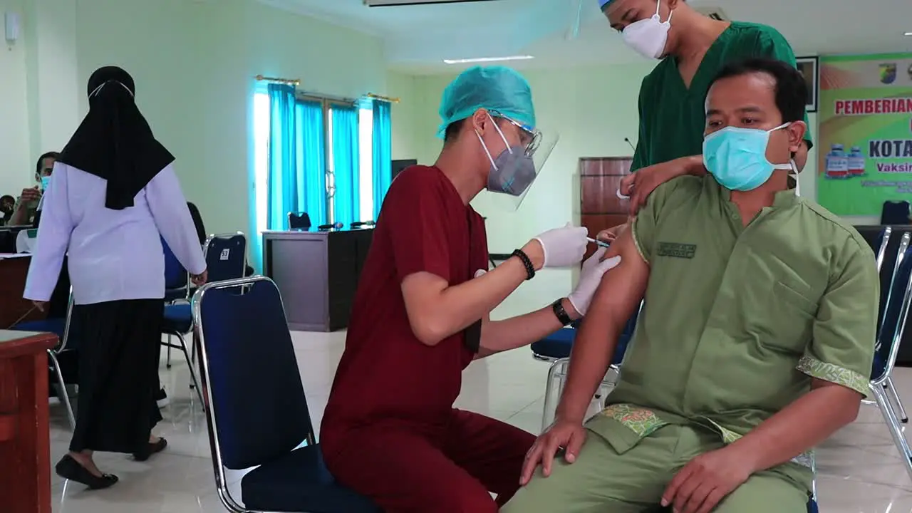 very noise and film grain clip doctor holding syringe and using cotton before make injection to patient in medical mask Covid-19 or coronavirus vaccine Pekalongan Indonesia Februari 11 2021