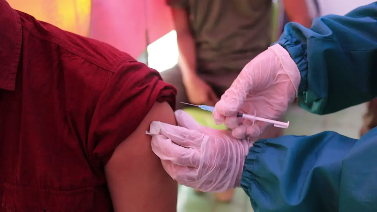 very noise and film grain clip doctor holding syringe and using cotton before make injection to patient in medical mask Covid-19 or coronavirus vaccine