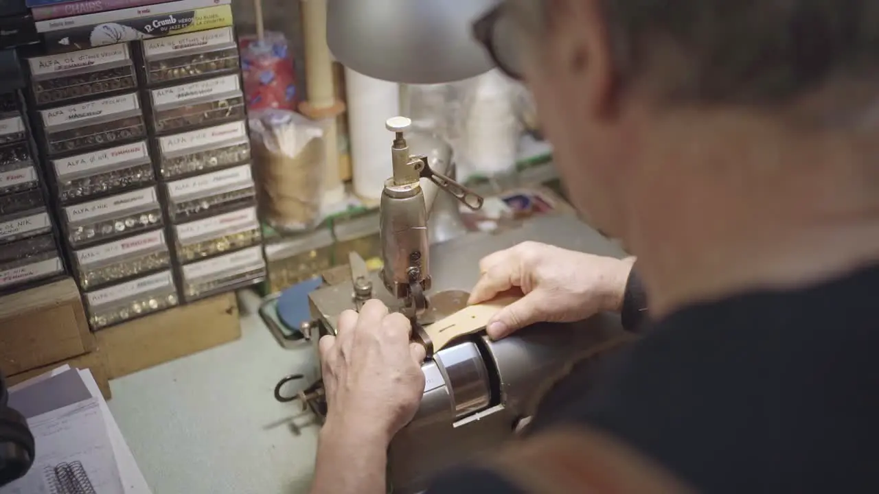 shoulders view of a leather craftsman while thinning leather belt