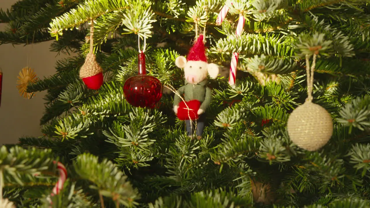 Scandi Style Decorated Christmas tree with colorful ornaments and festive mouse figure on daytime