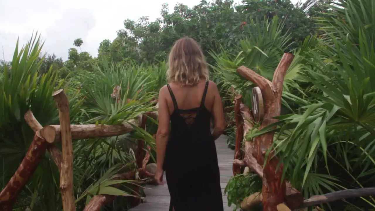 blonde woman walks on a wood bridge in the jungle