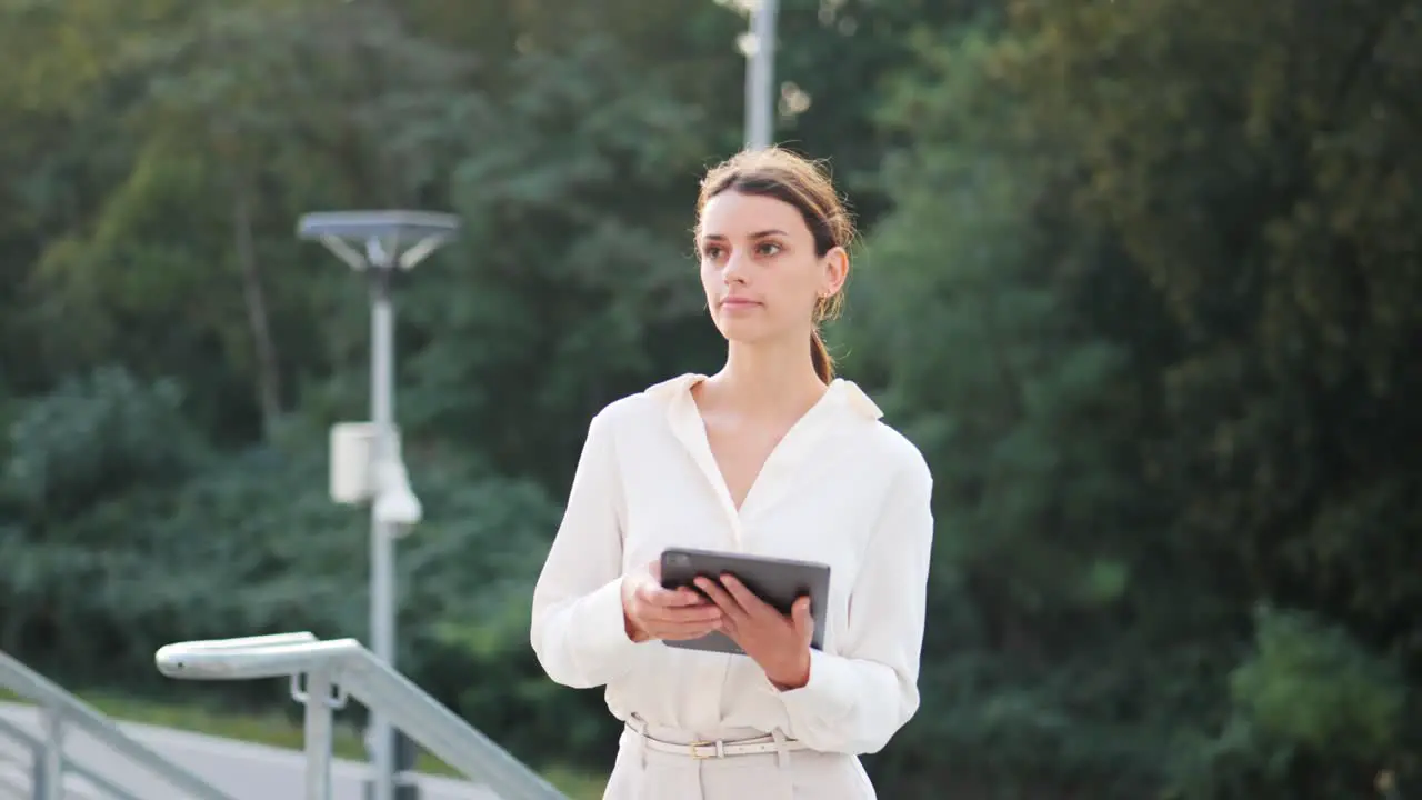 Young attractive businesswoman walks up the stairs with a tablet in her hand