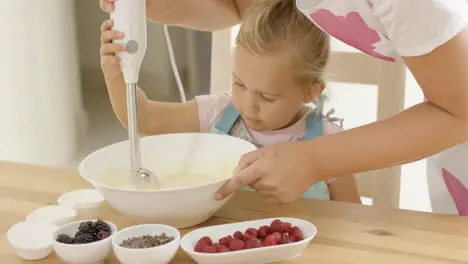 Cute little girl learning to bake from mother