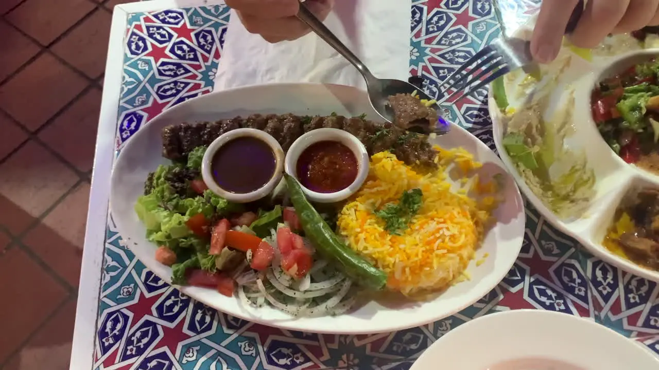 A mediterranean turkish dish on a plate with man hands holding cutleries