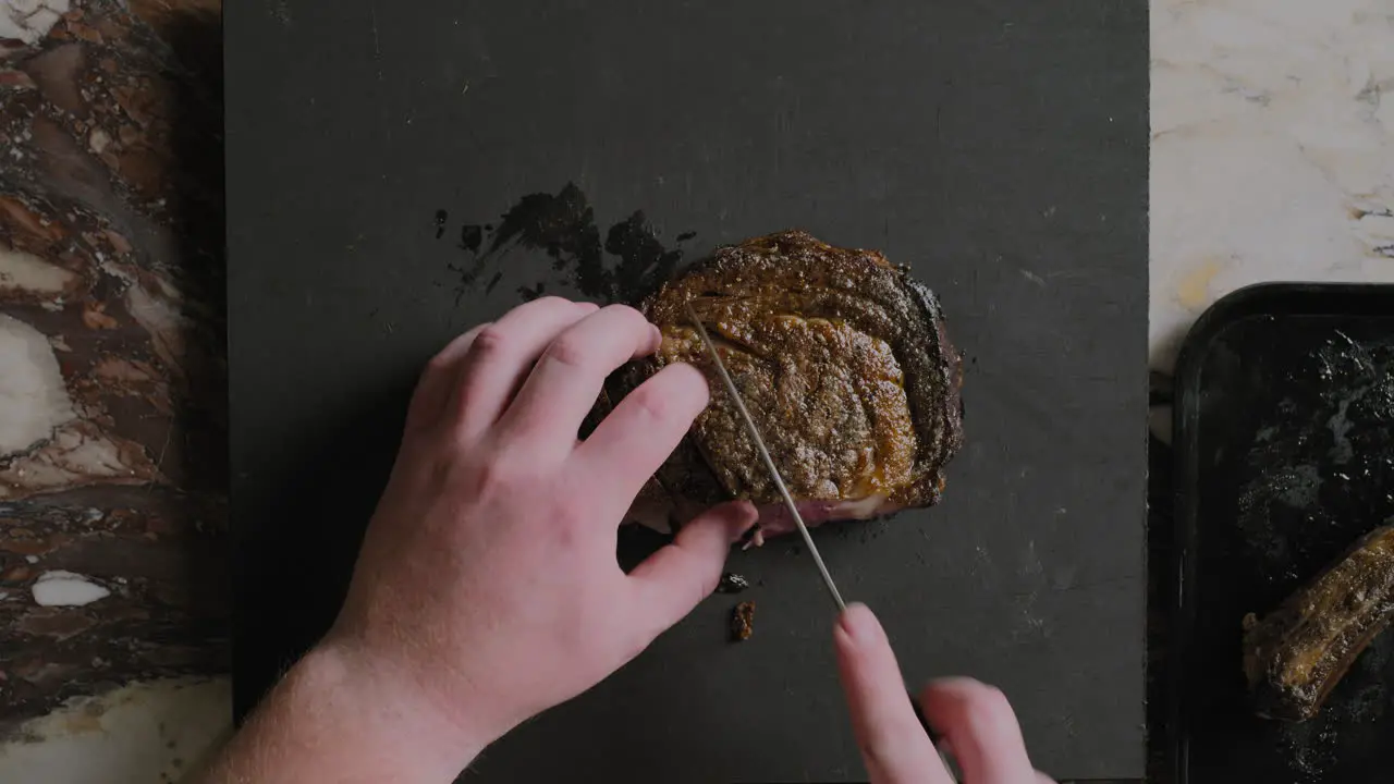 Top down shot of a ribeye steak being sliced on a cutting board