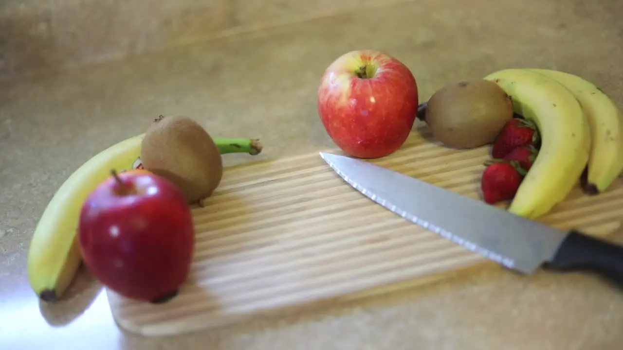 Slow Motion shot of a variety of fruits on a cutting board with a knife laying next to them