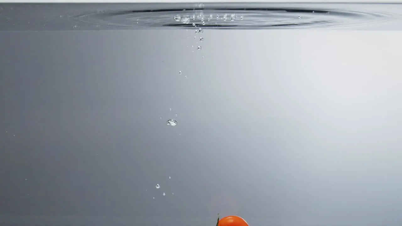 Cherry tomatoes falling into clear water